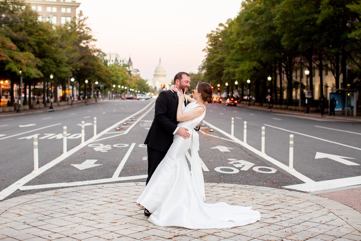 Bride and groom about to kiss with the Capitol in the background.